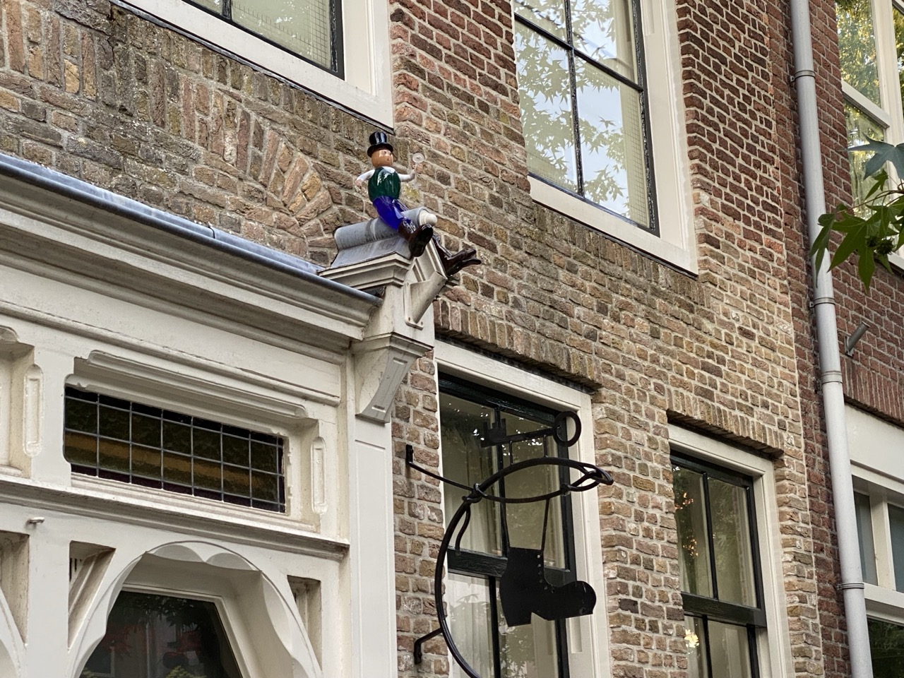 Glazen ornament van een mannetje wat zit met een hoge hoed op