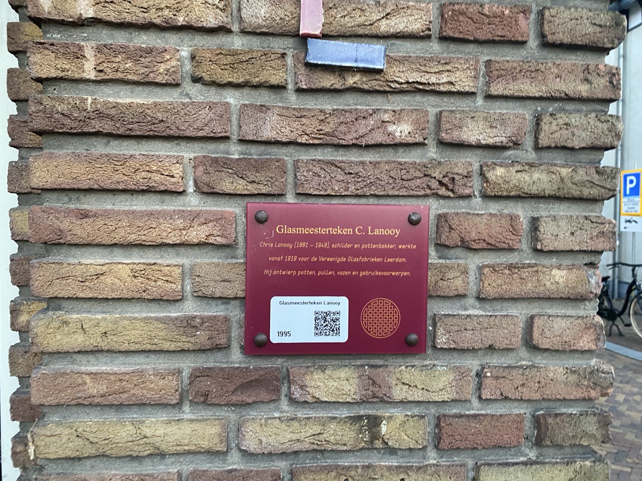 Bordjes die je overal in het centrum kan vinden met daarop een beschrijving en een QR code.  In dit geval beschrijft het bordje een glas meester. 